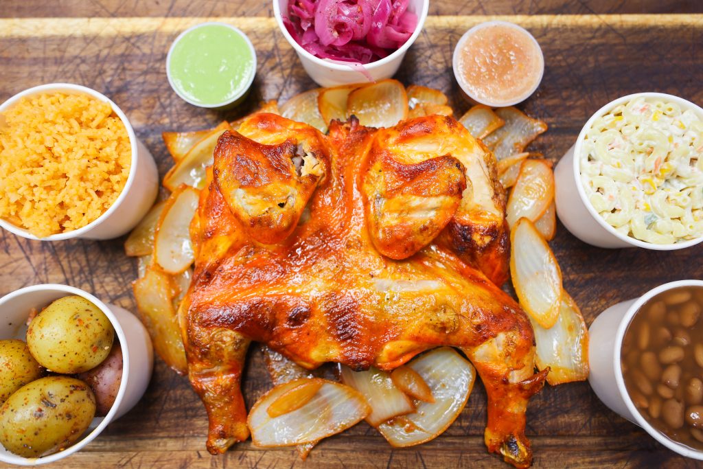 Grilled chicken on top of grilled onions and surrounded by potatoes, rice, beans, mac salad, purple onions and salsa at Los Compadres 2.